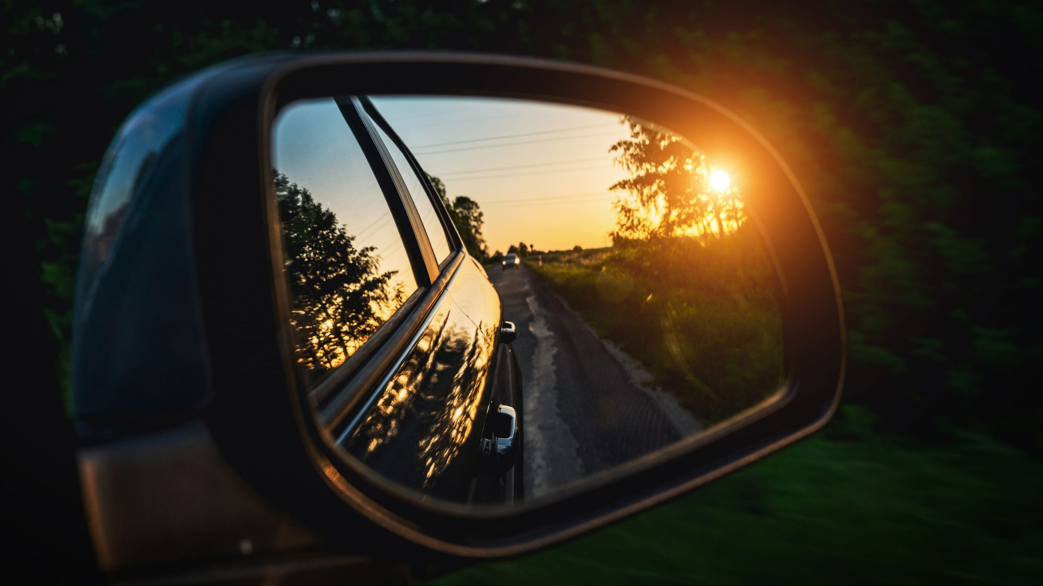 car in rear view mirror with sunset