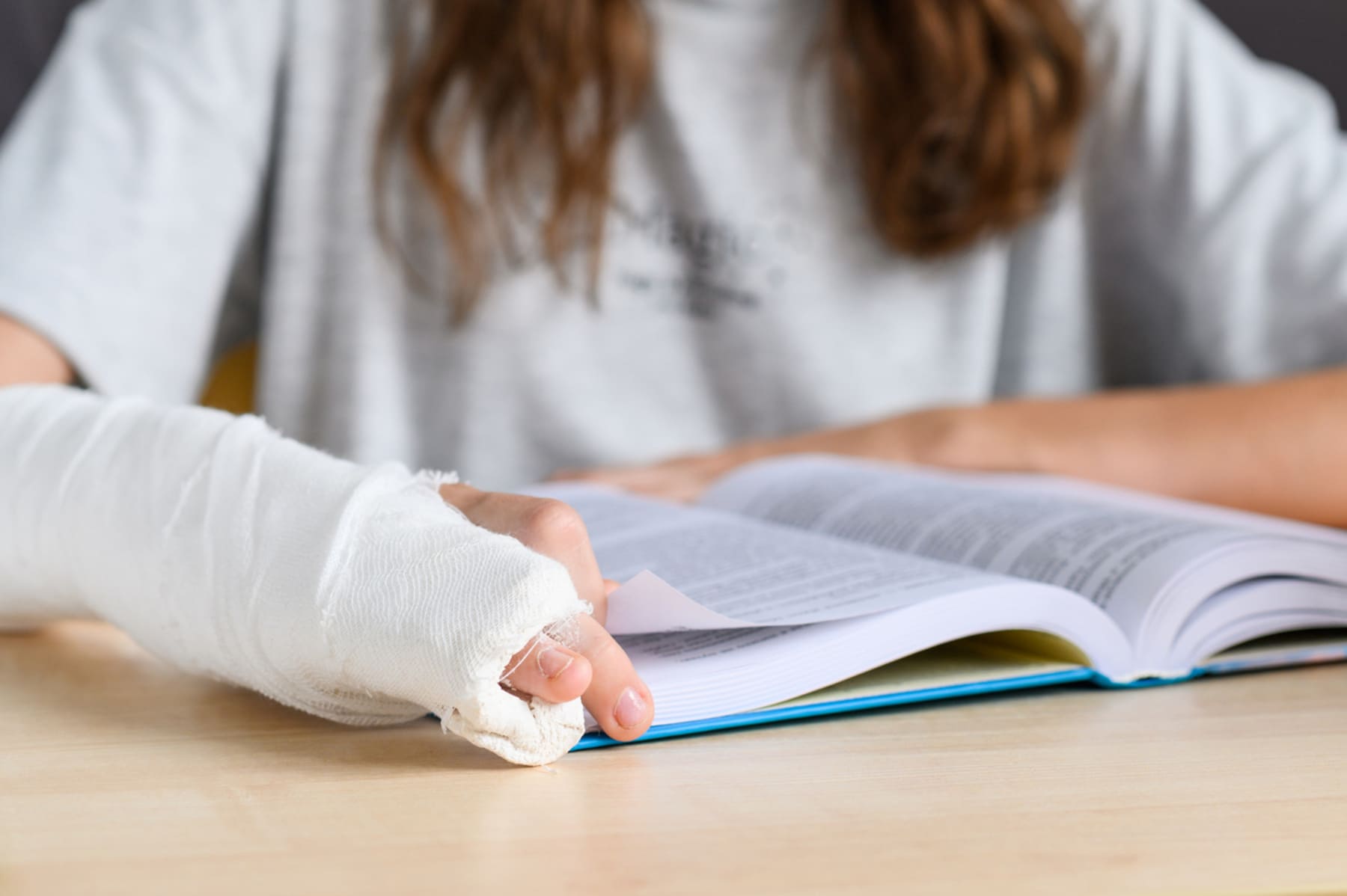 School student wearing a cast and reading a book