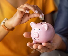 girl putting a coin in the money bank