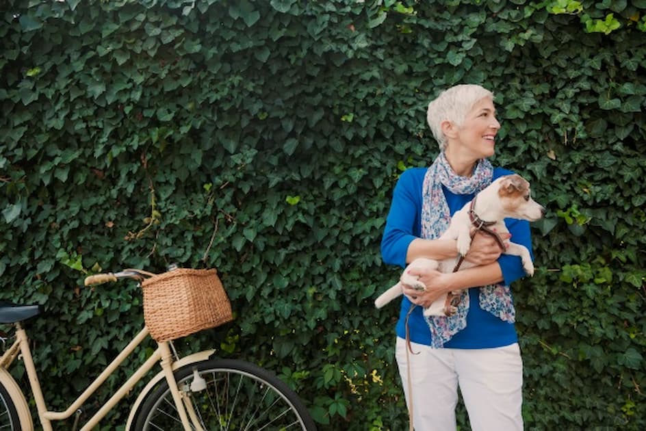 woman holding dog whilst standing beside bike