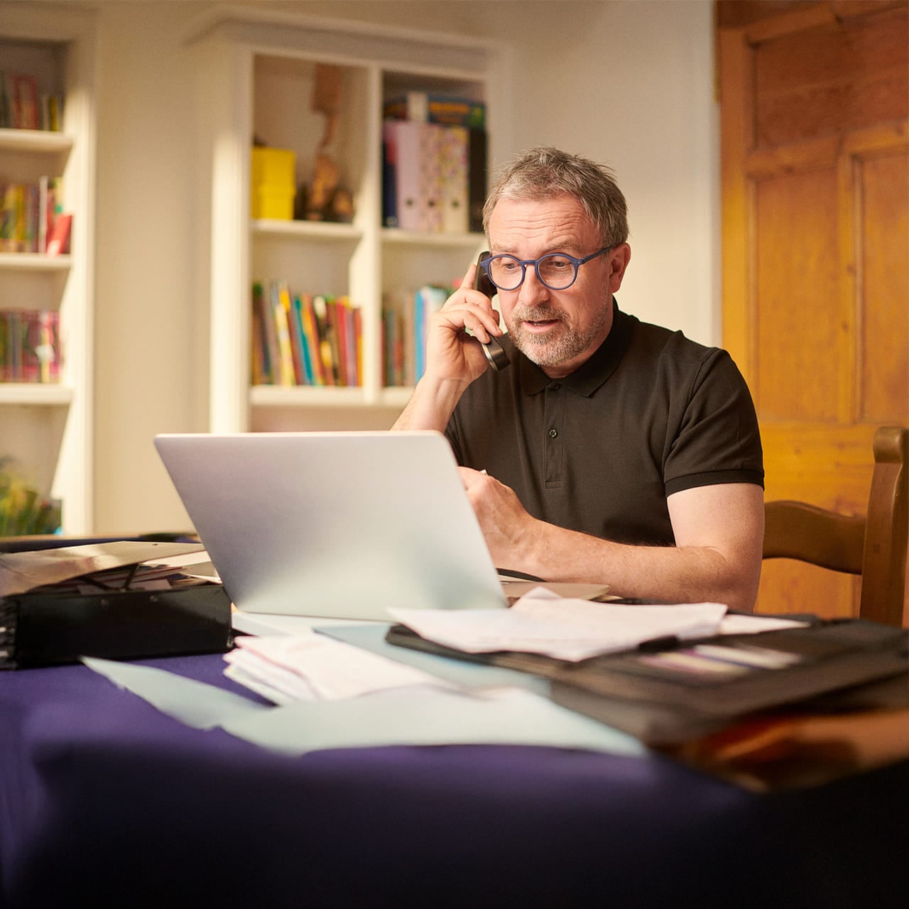 Man on phone at desk with laptop