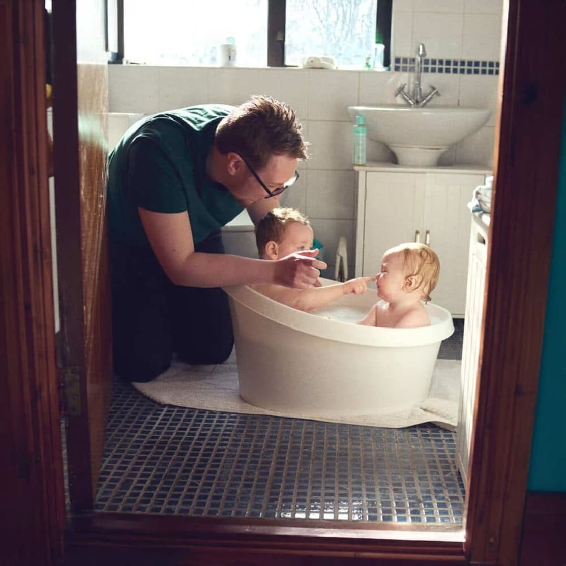 Father bathing babies at home in baby bath