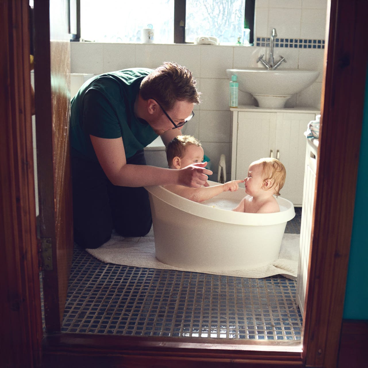 Father bathing twin babies